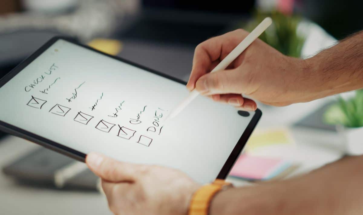 Hand using a stylus on a digital tablet checklist
