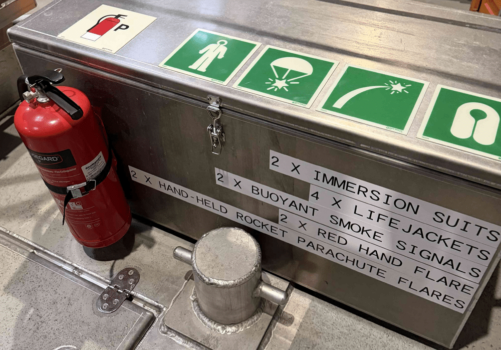 Safety equipment box on an EMSA oil recovery vessel, with markings for immersion suits, life jackets and flares
