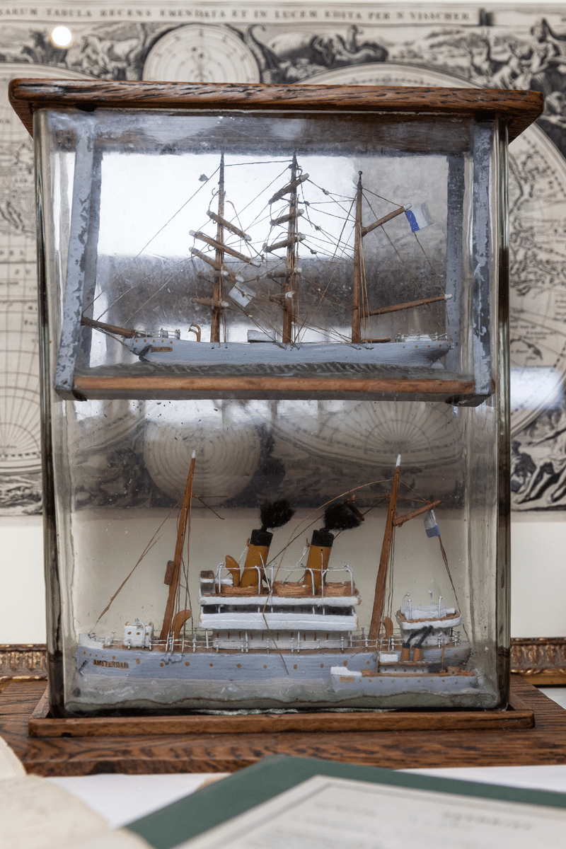 Glass case with two ship models: a sailing ship above and a steamship below
