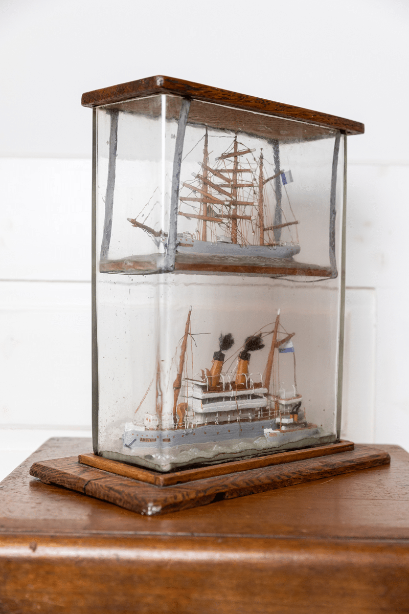Glass case with two ship models on a wooden base